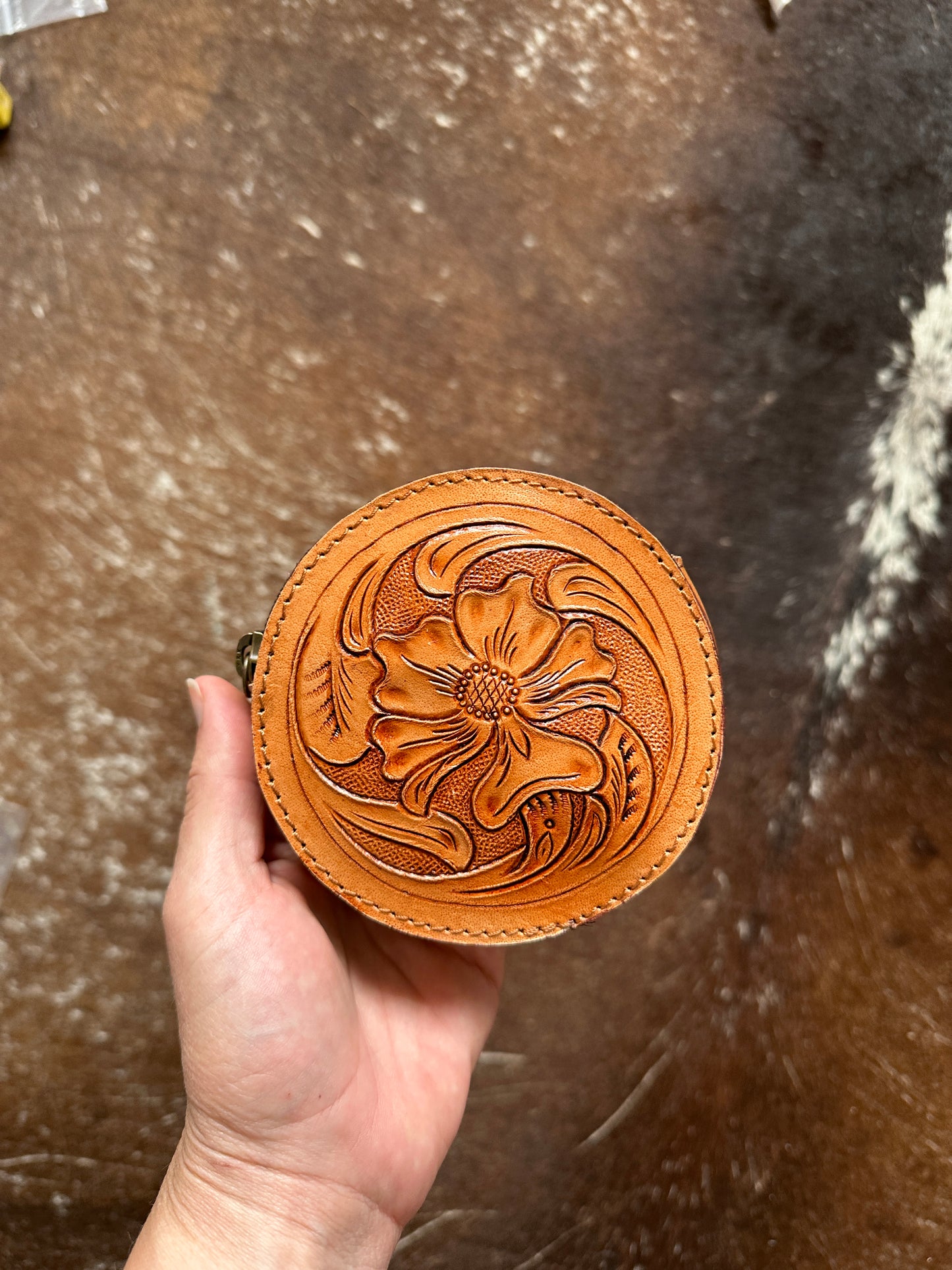 Round leather coin purse floral hand tooled front, plain back. Zip closure.