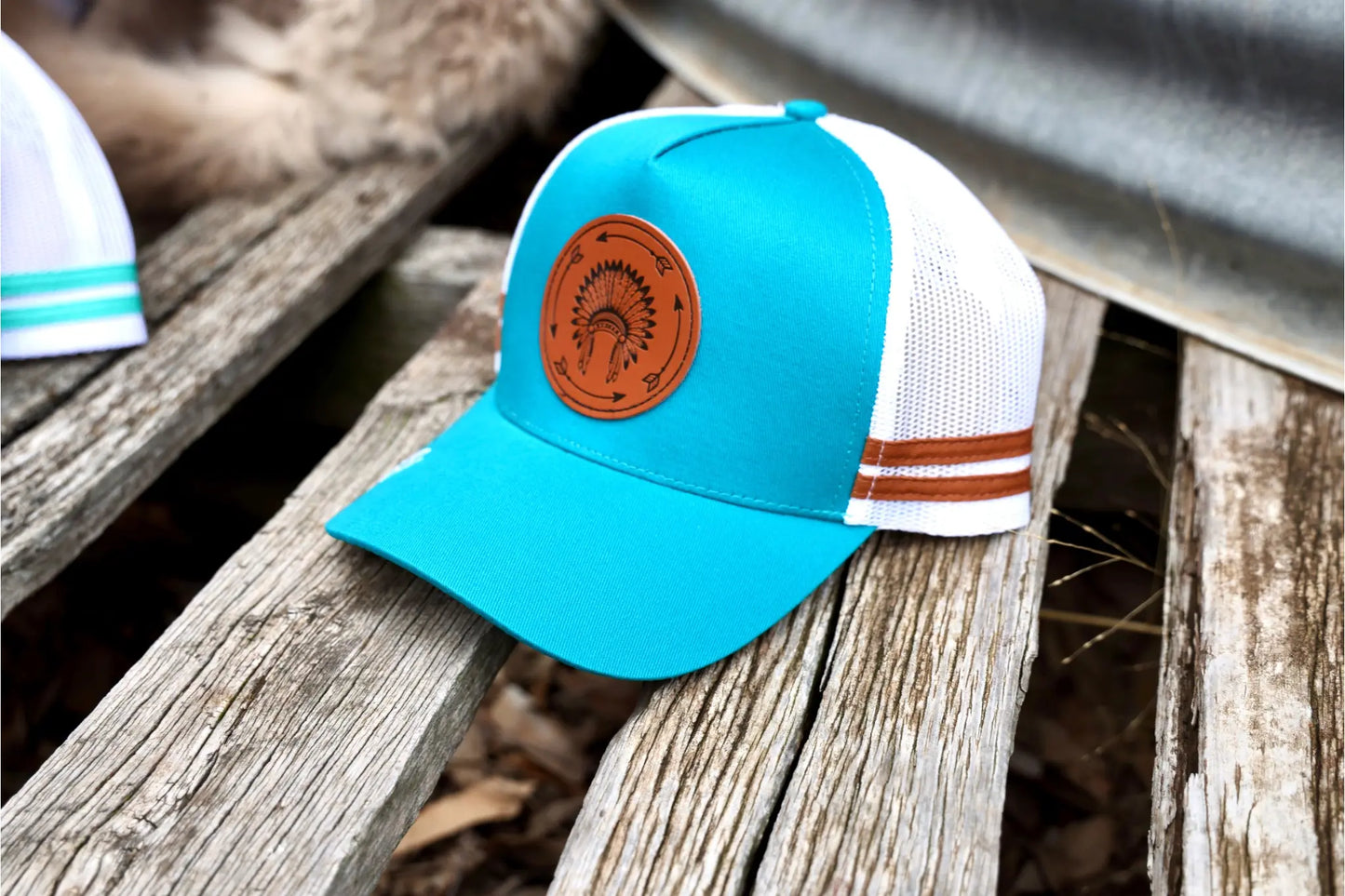 Teal blue Trucker cap with leather patch, Indian headdress + arrow.
Teal blue cap, under-brim cream Indian theme patterns.
White mesh & snapback.